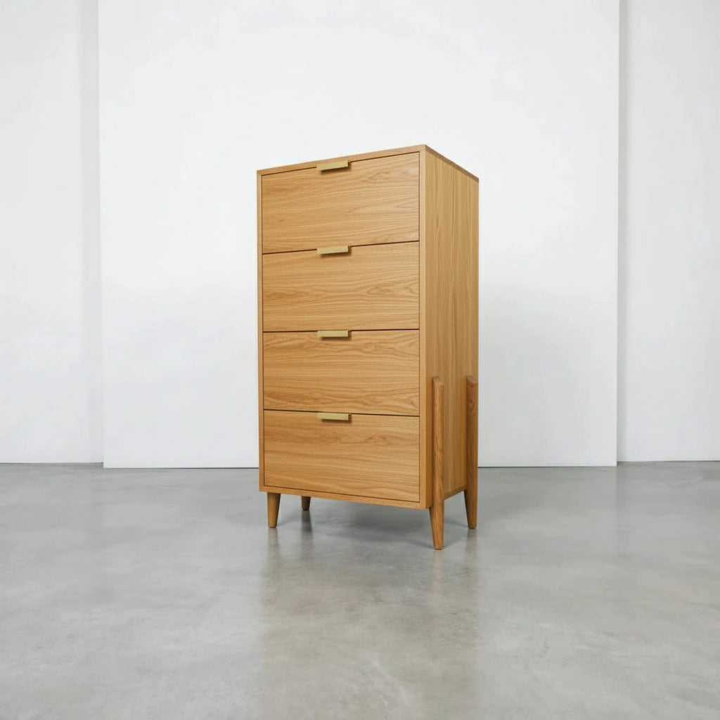 The TY Fine Furniture Apollo Tall Dresser is a solid wood piece with four drawers, simple handles, and tapered legs. Its modern, minimalist design stands out on a smooth light gray floor against a plain white wall.