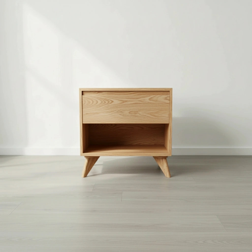 The TY Fine Furniture Modern Cube Side Table in White Oak features a minimalist design with angled legs, a push-to-open drawer, and an open shelf, shown on a light floor against a plain white wall.