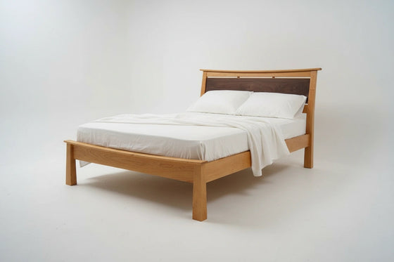 The Enso Platform Bed Cherry by TY Fine Furniture, featuring a dark wood headboard and dressed in white sheets and pillows, is set against a plain white background.