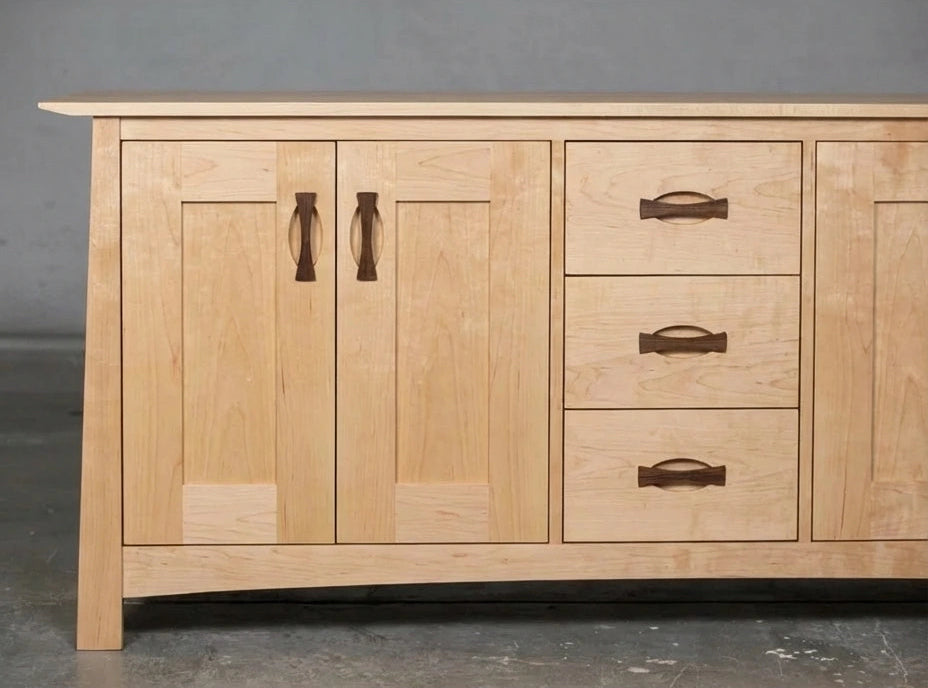 The Enso Solid Wood Credenza by TY Fine Furniture is a handmade maple buffet with two left cabinet doors, three right drawers, and dark wood handles that contrast the natural finish—perfect for sustainable dining room storage.