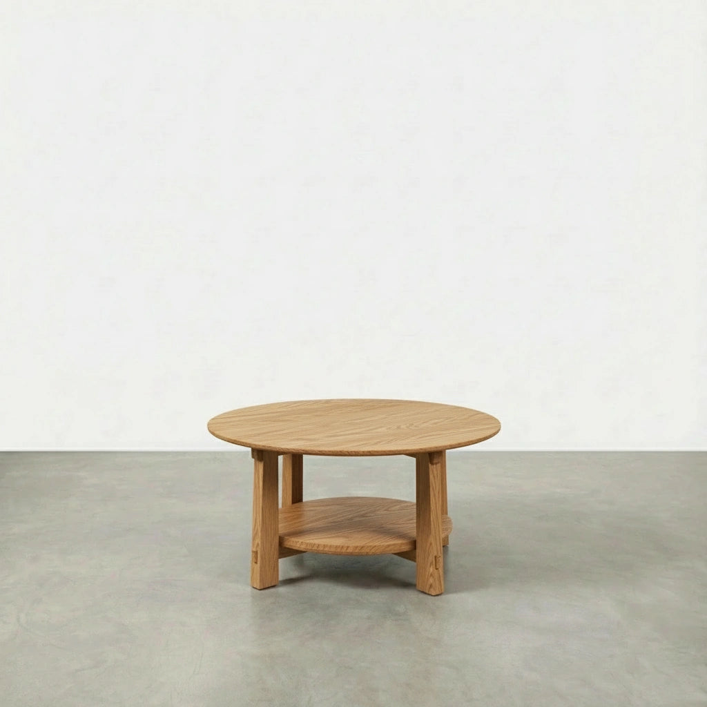 A TY Fine Furniture Enso Round Coffee Table, handcrafted in Ohio from white oak, stands on a gray concrete floor against a plain white wall.