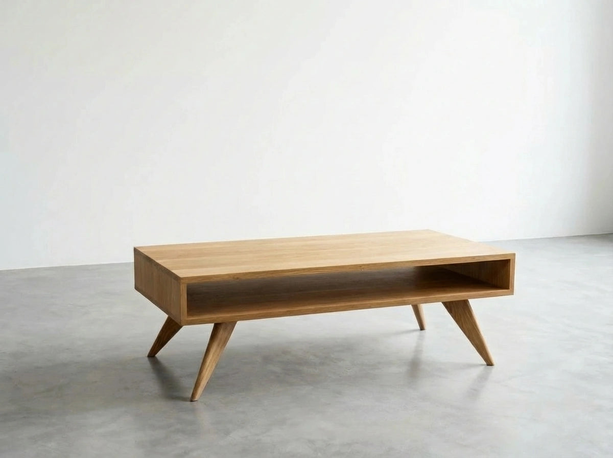 The Modern Coffee Table by TY Fine Furniture is a handmade, solid white oak piece inspired by Mid-Century Modern design, featuring angled legs and an open shelf—perfect for minimalist spaces.