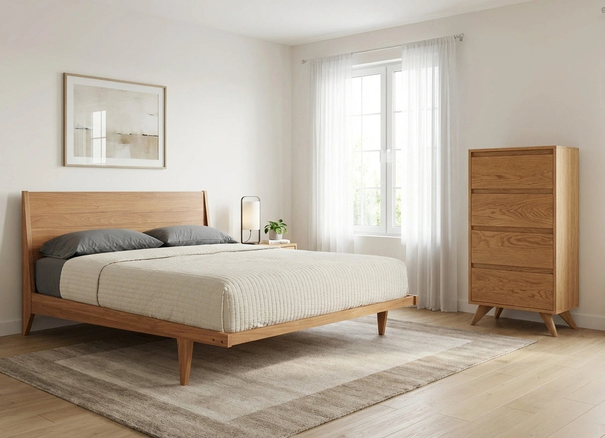 A minimalist bedroom features the TY Fine Furniture Tall Modern Dresser Mid Century in White Oak, a wooden bed frame with gray pillows and beige bedding, a lamp and potted plant by sheer white curtains, light wood floors, and a neutral rug.