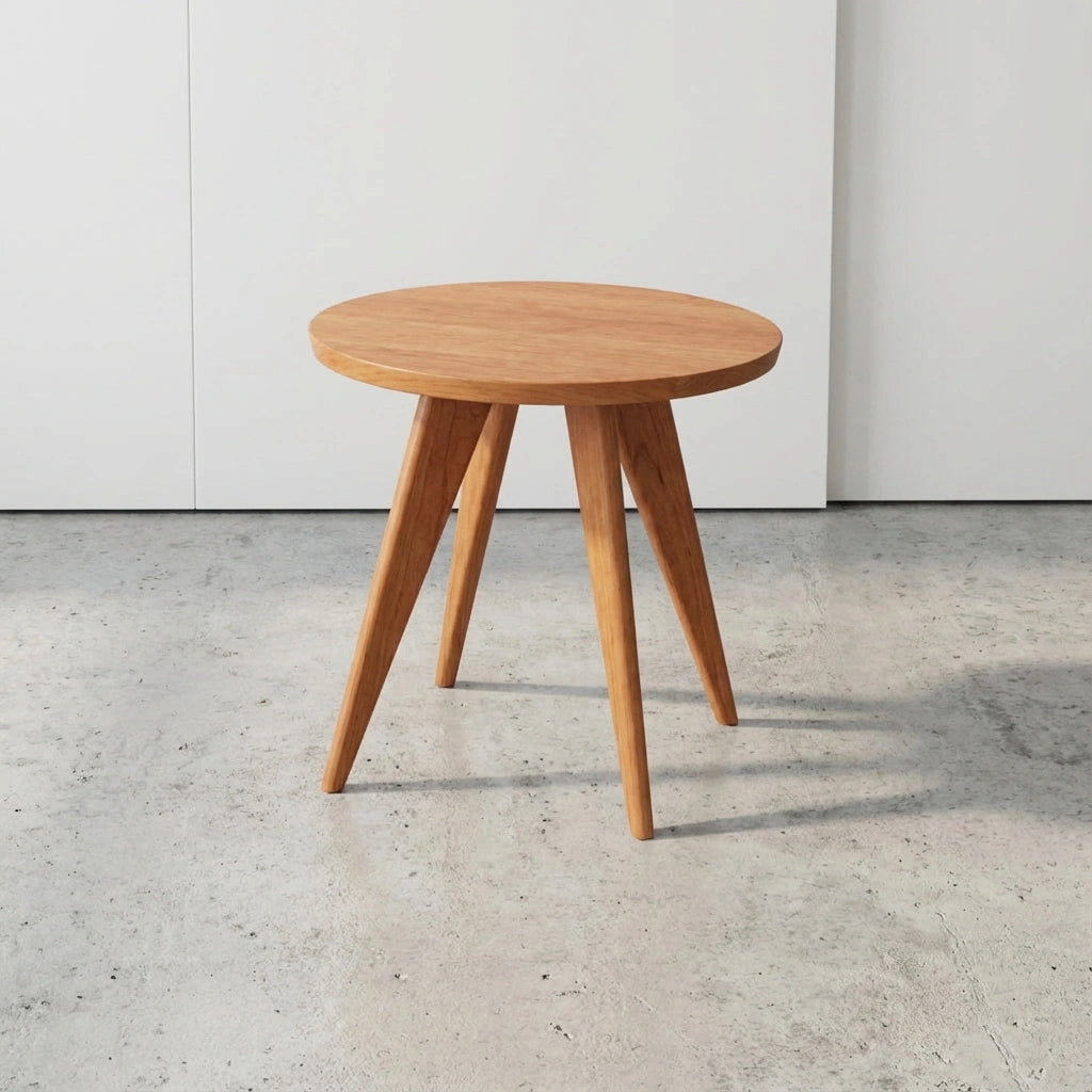 The Essentials Solid Wood Round Side Table by TY Fine Furniture, handcrafted in cherry in Columbus, Ohio, stands on a light gray concrete floor against a plain white wall, bringing mid-century modern flair to the space.