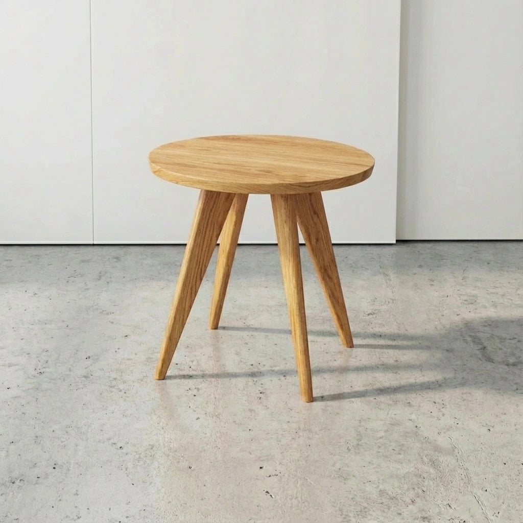 The Essentials Solid Wood Round Side Table by TY Fine Furniture, handcrafted in Columbus, Ohio from white oak, features a small round design with three angled legs—bringing Mid-Century Modern charm to any space.