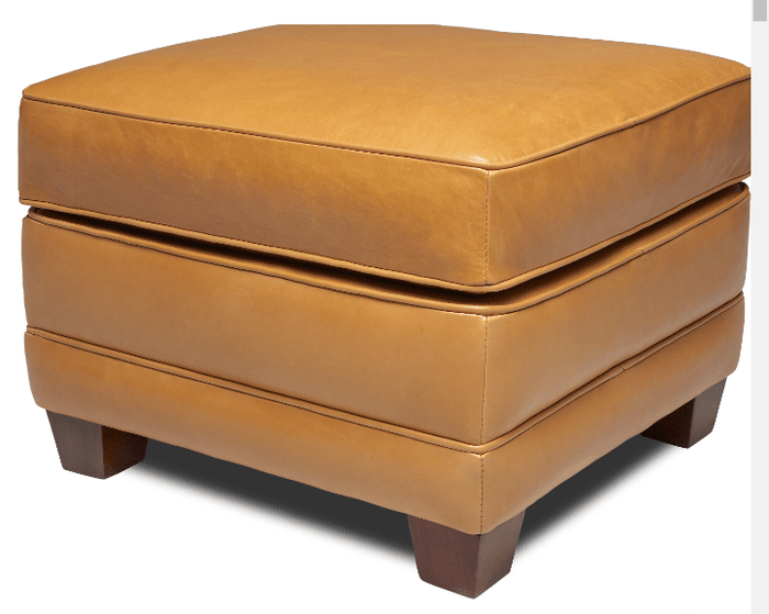 A tan leather ottoman with a square shape and four wooden legs.